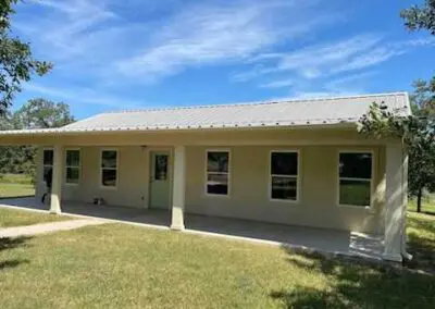 Shower with light blue subway tile walls, recessed niche with glass shelf, chrome handheld showerhead and controls, white pebble-pattern floor tile and small frosted window at top left